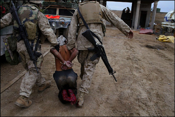 Fallujah, Iraq, November 12, 2004 - An Iraqi teenager who was captured taking cover in a mosque is dragged by U.S. Marines to a transport truck for interrogation at a makeshift detention and prisoner sorting center in the city's train station.  Frédéric Lafargue