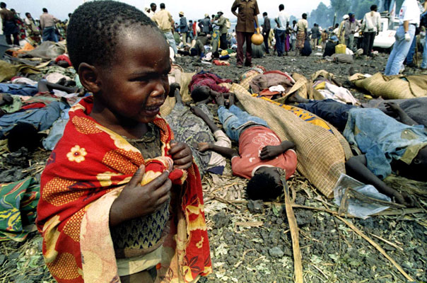 A Rwandan child cries next to his dead parents bodies (background) at a refugee camp, 10 kilometres outside Goma, Zaire, July 21, 1994. Thousands of exhausted Hutu refugees fleeing Tutsi troops ended up in this camp, only to succumb to a cholera epidemic. The child was later picked up and sent to an orphanage. © Jack Dabaghian
